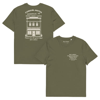 Two olive green short-sleeve t-shirts shown on a plain white background, displaying the front and back designs. The back shirt features a large white graphic of a building with 'Cowgirl Notes' text, while the front shirt has small white text on the left chest.