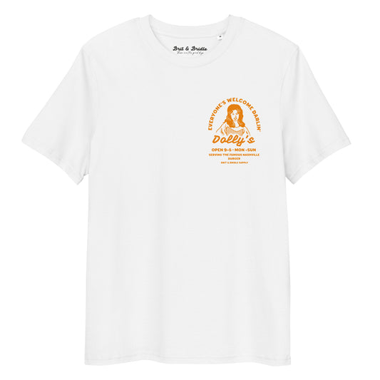 A white short-sleeve crewneck t-shirt with a vintage-style orange graphic on the left chest. The graphic features a stylized portrait of Dolly Parton with the text 'Everyone's Welcome at Dolly's' and 'Dolly's Open 9-5 Mon-Sun'.