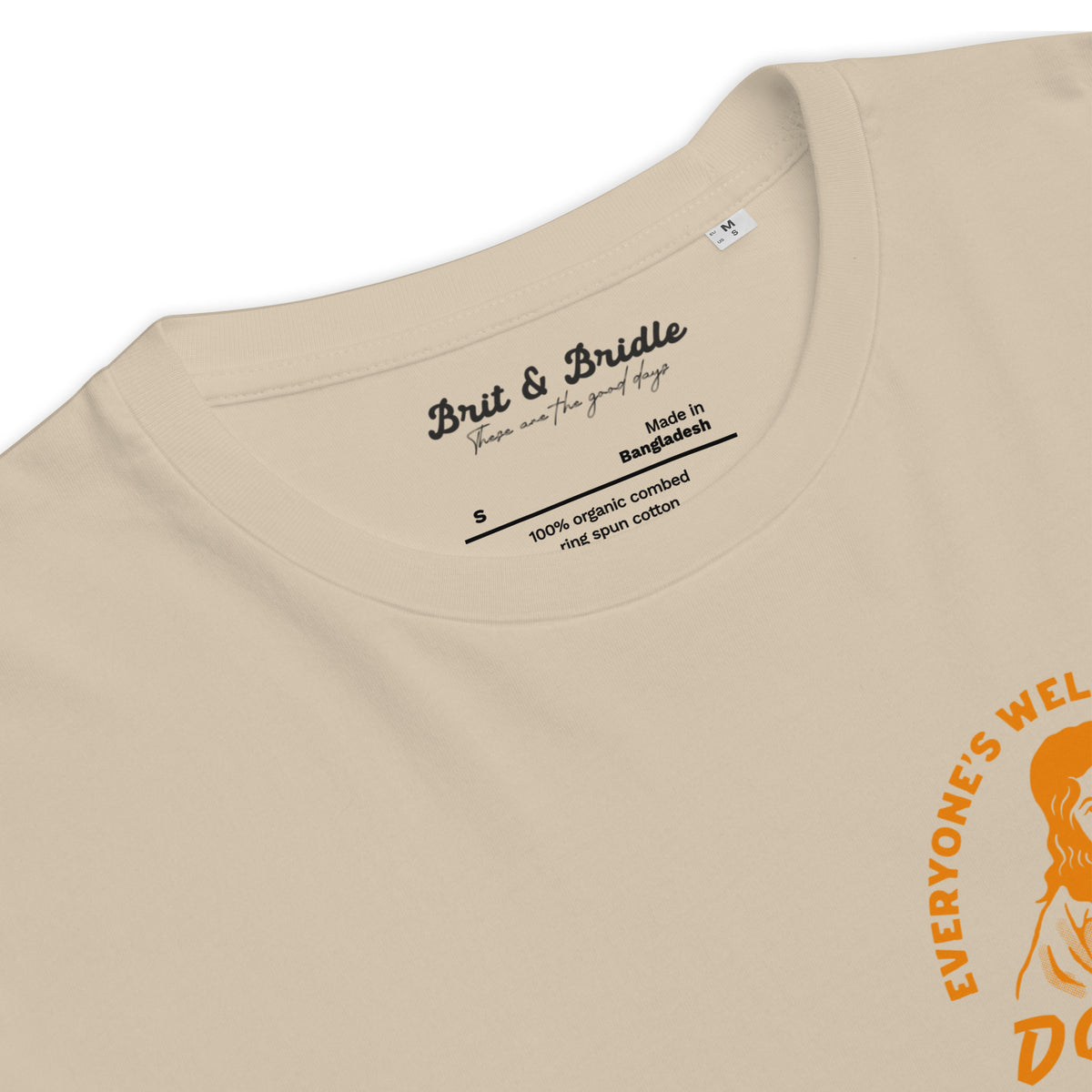 Close-up of a beige crewneck t-shirt showing the inner neck label for 'Brit & Bride' and a partial orange graphic print on the right side.